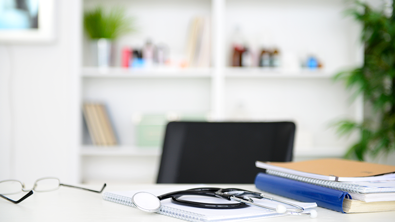 Desk with glasses, a stethoscope and spiral notebooks
