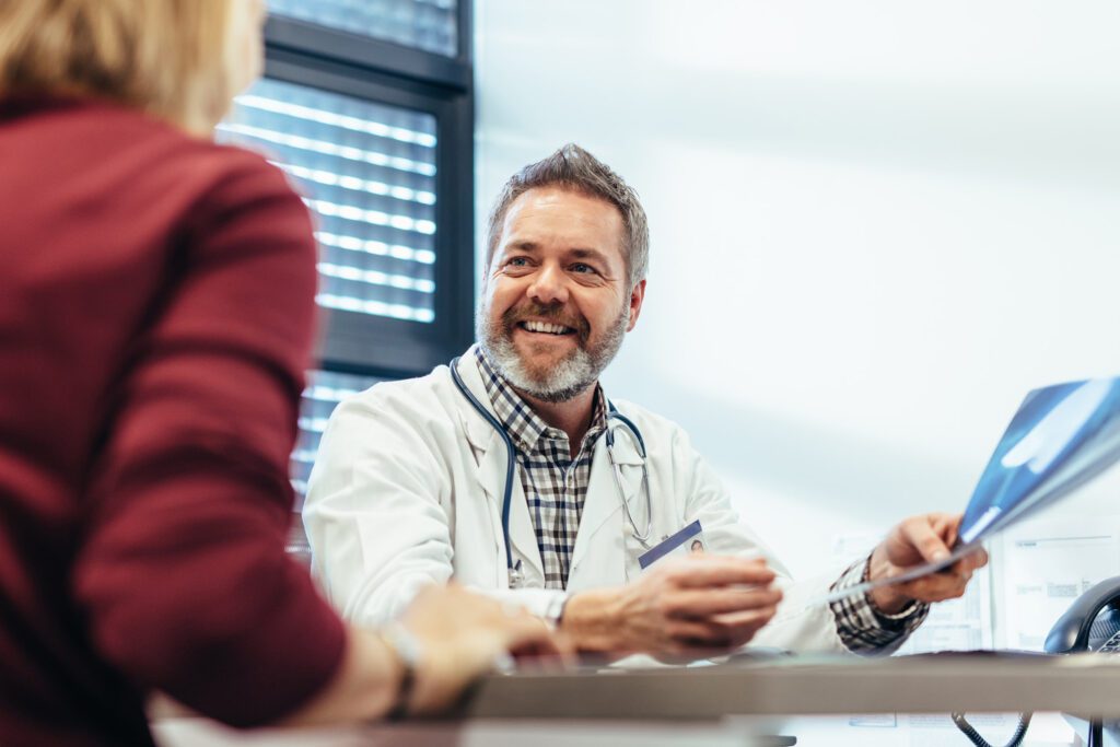 Smiling male doctor discussing X-ray results with a female patient in a clinic