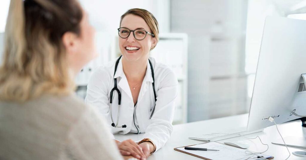 Smiling female doctor in conversation with a patient during a consultation in her office