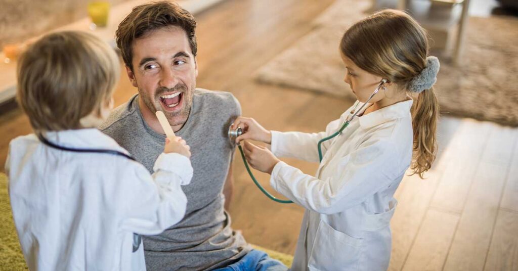 Young boy and girl dressed as doctors playing with their dad