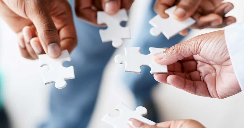 Hands of diverse individuals holding and connecting puzzle pieces together