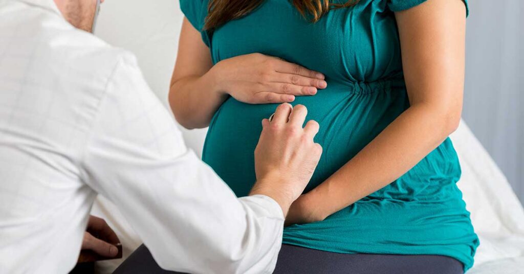 Doctor examining a pregnant woman with a stethoscope on her belly