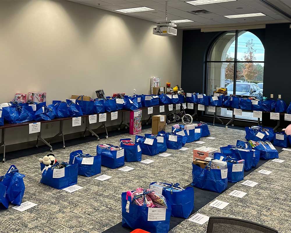 Room filled with blue bags of holiday donations organized on the floor and tables