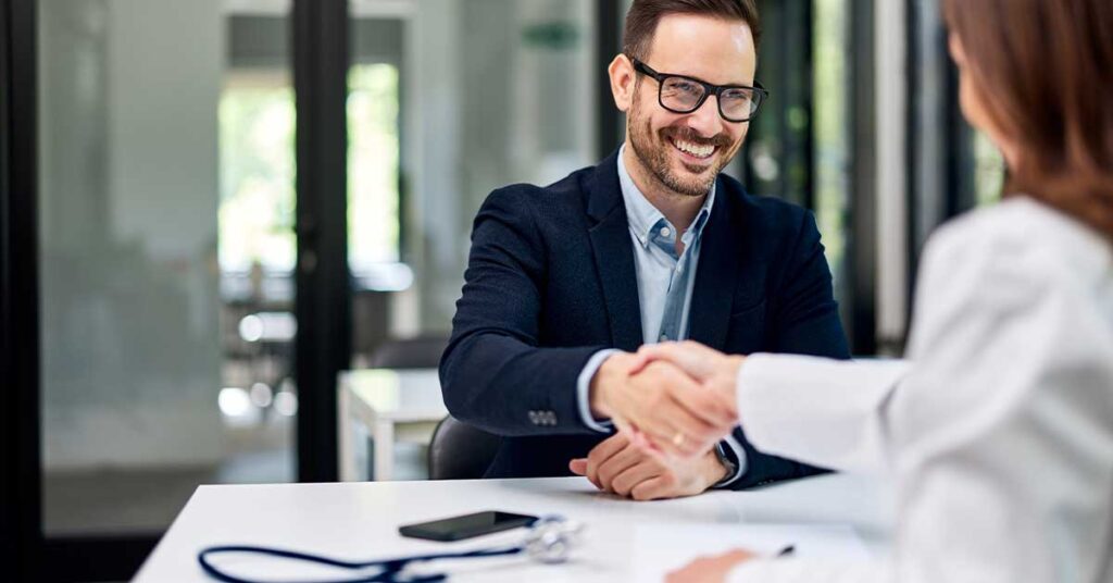 Smiling candidate shaking hands with a recruiter during a physician executive job interview