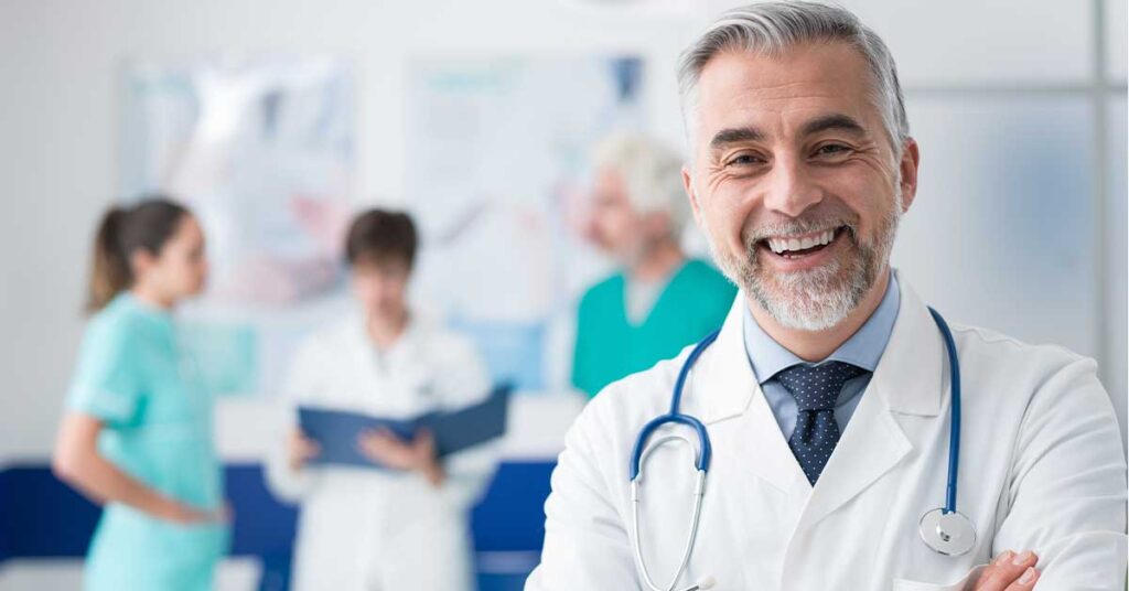 Smiling male doctor in front of a medical team in a healthcare