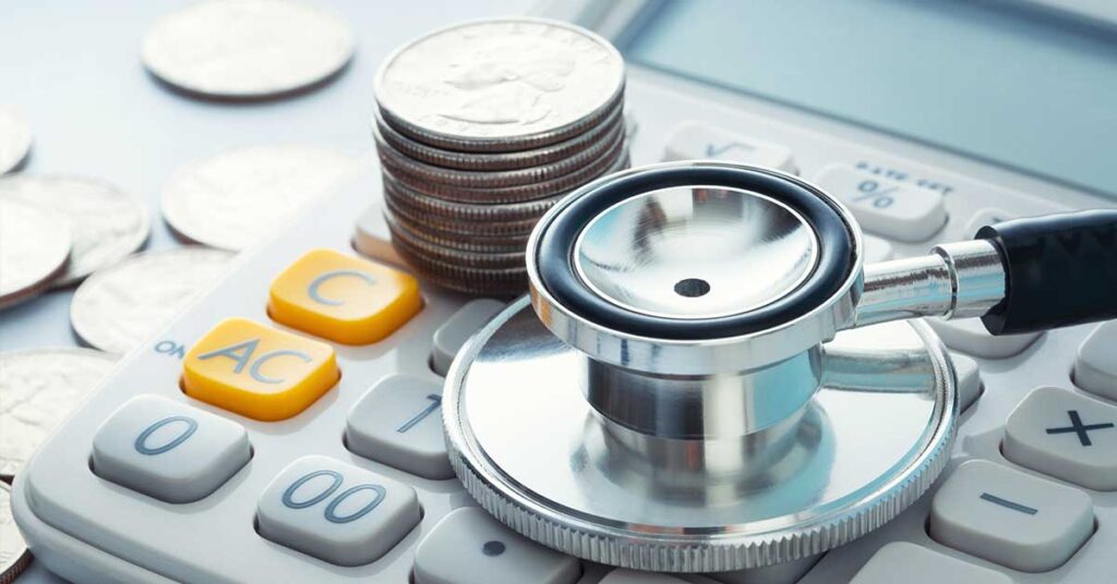 Stethoscope placed on a calculator with a stack of coins