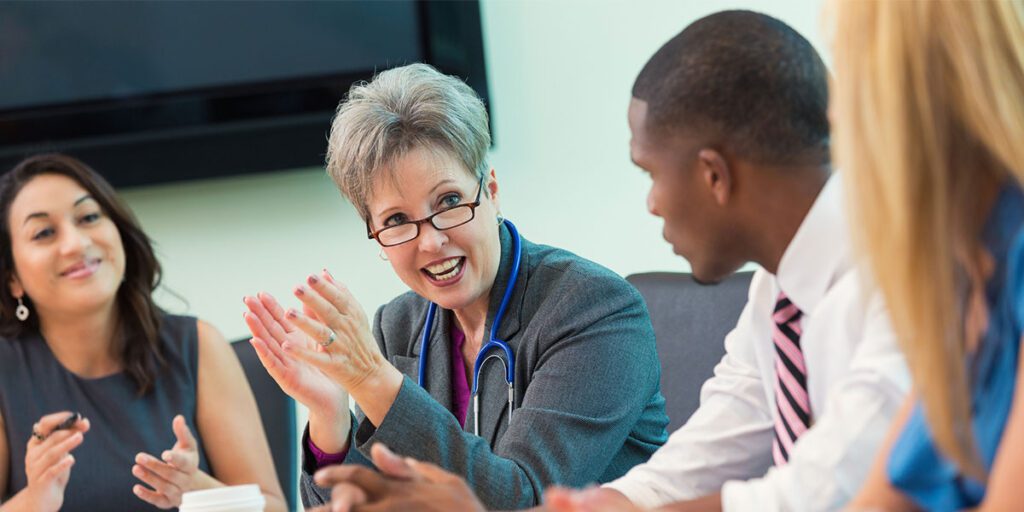 Healthcare professionals having a discussion in a meeting room, with a female doctor leading the conversation