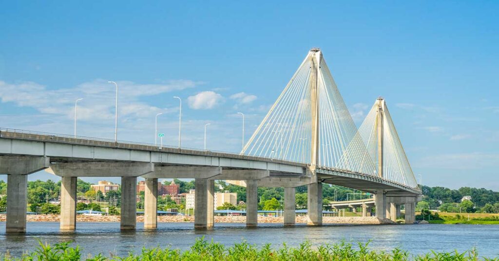 Cable-stayed bridge over a river with a blue sky and urban background