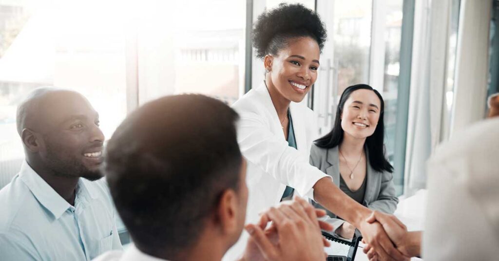 Smiling Doctor in white coat shaking hands in a business meeting