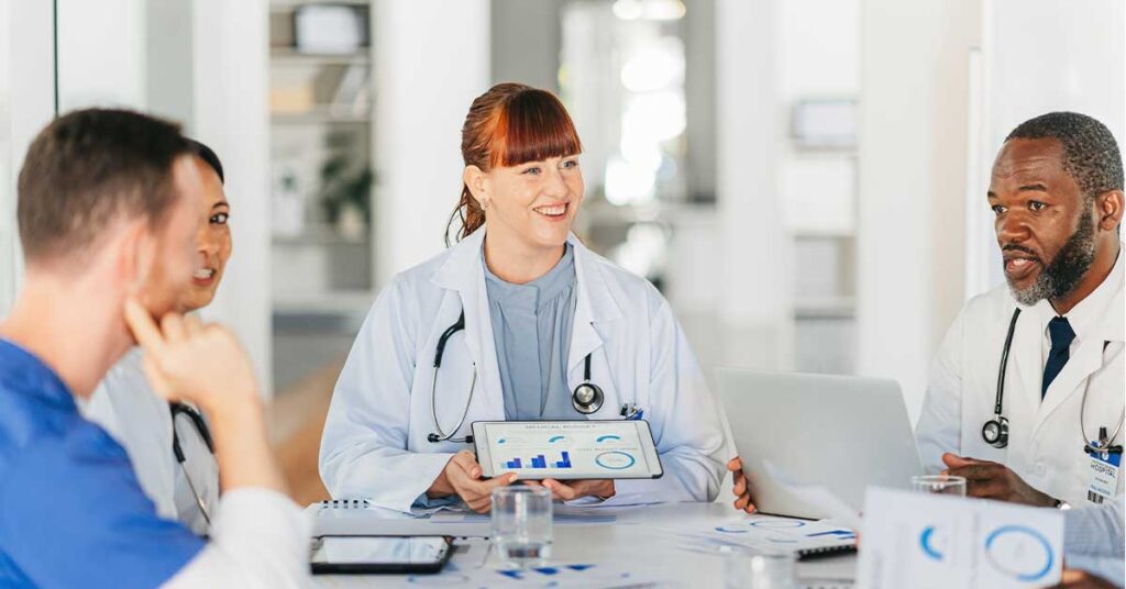 Doctors discussing patient data on tablets in a medical meeting room