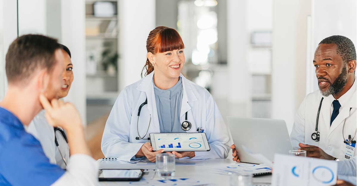 Doctors discussing patient data on tablets in a medical meeting room