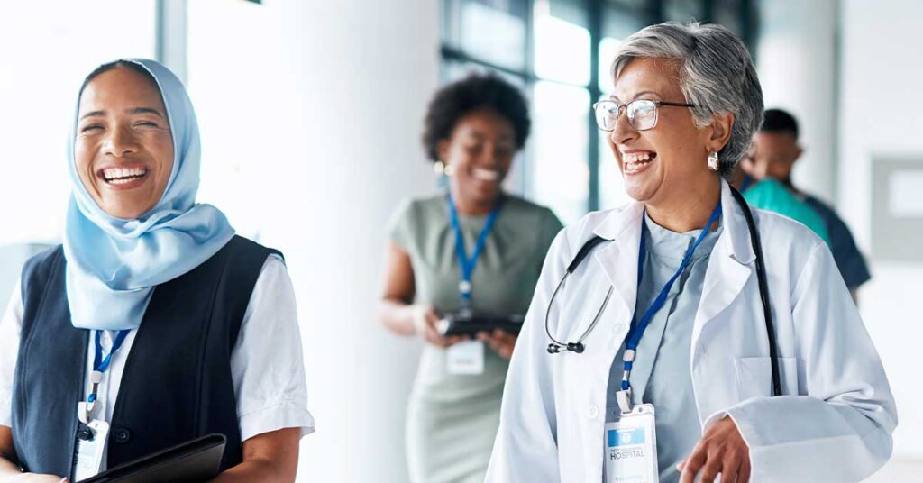Diverse group of healthcare professionals smiling and walking in a hospital hallway