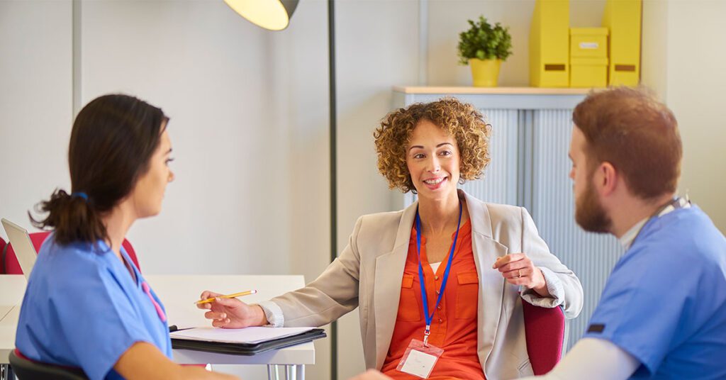Professional woman leading a meeting with two nurses in a modern office space