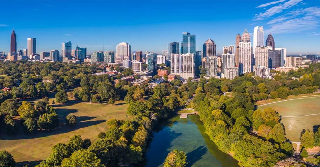 Aerial view of a city skyline with a sprawling green park and a river in the foreground