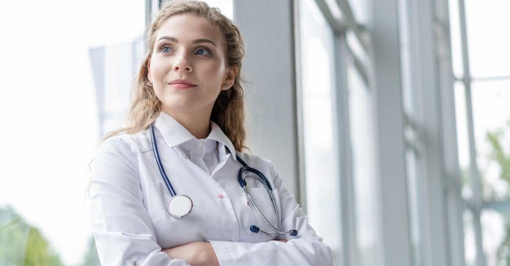 Confident female doctor with stethoscope, standing near large windows in a modern medical facility
