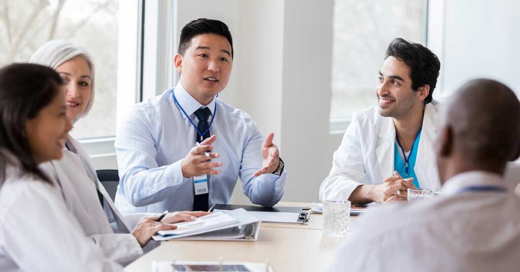 Diverse healthcare professionals engaged in a team discussion around a conference table in a bright office