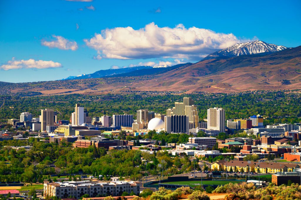 City skyline with modern buildings against a backdrop of mountains and a clear sky