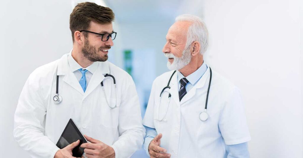 Young male physician having a pleasant conversation with an older male physician in a hospital
