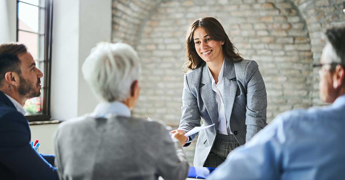 Female candidate handing administrators a resume.