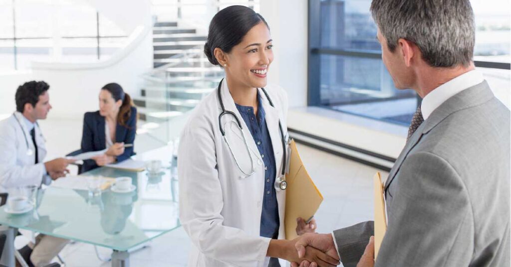 Woman doctor shaking hands with hospital executive