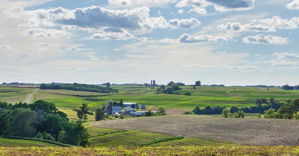 Iowa farms and fields on rolling hills under a beautiful cloudscape on a sunny summer afternoon