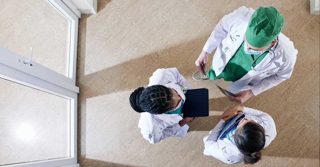 Medical workers in labcoats standing in clinic corridor