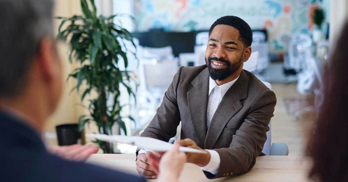 Smiling businessman handing over documents during a meeting