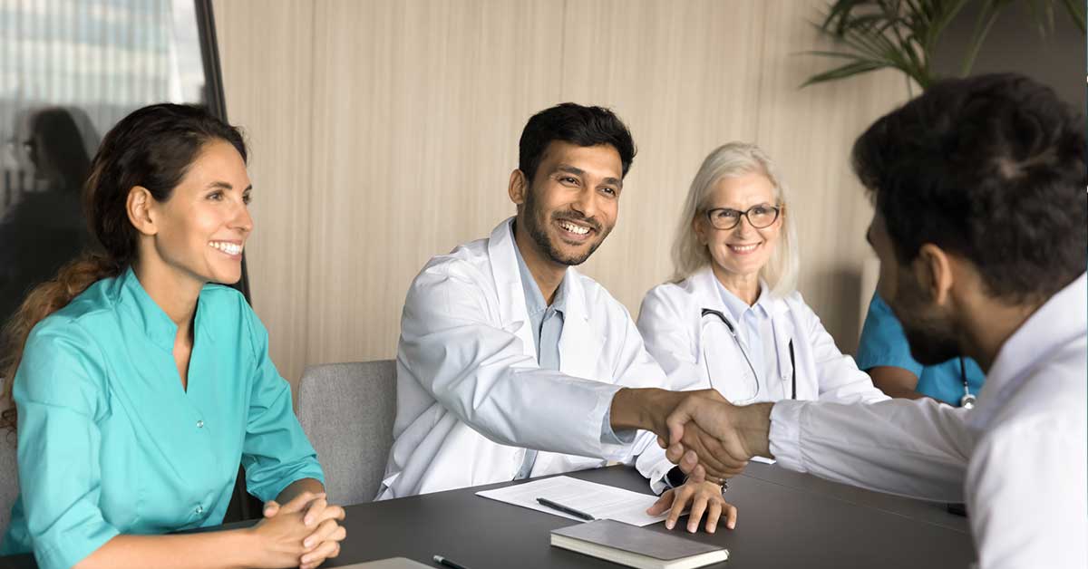 Positive confident physician shaking hands with colleagues