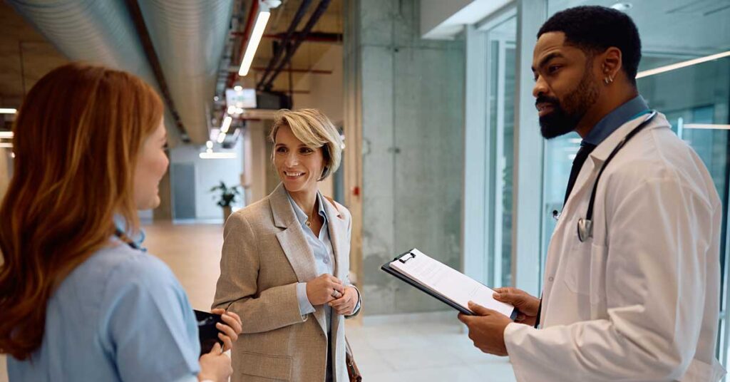 Happy businesswoman talking to medical experts in a hospital.