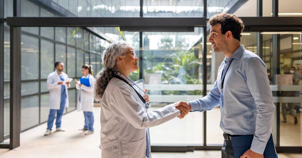 Administrator greeting a doctor with a handshake at the hospital