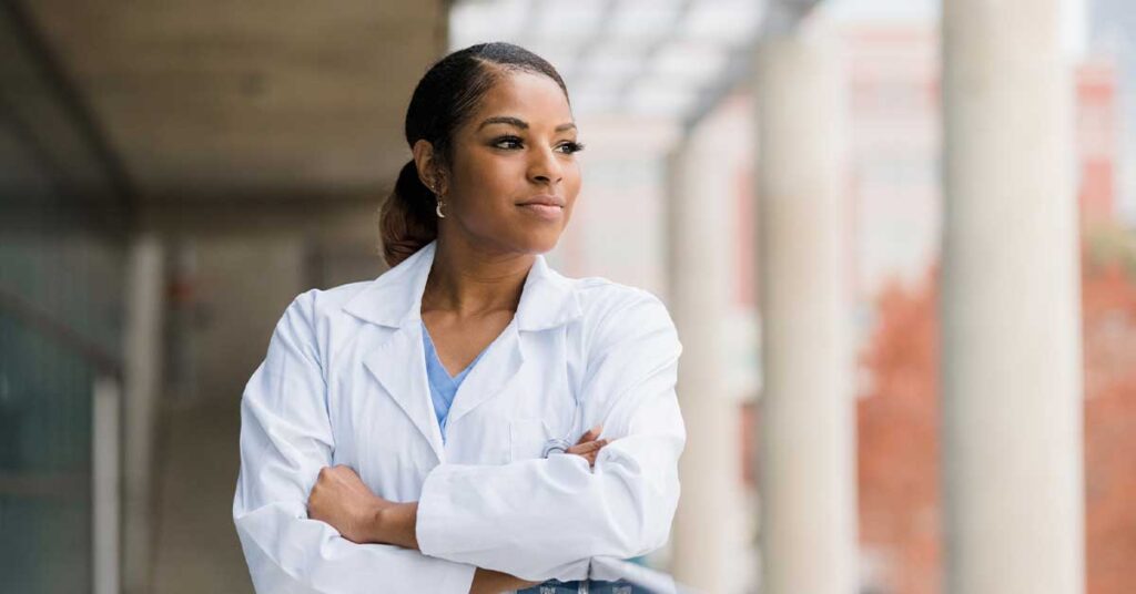 The mid adult female doctor leans against the railing on the balcony in the hospital