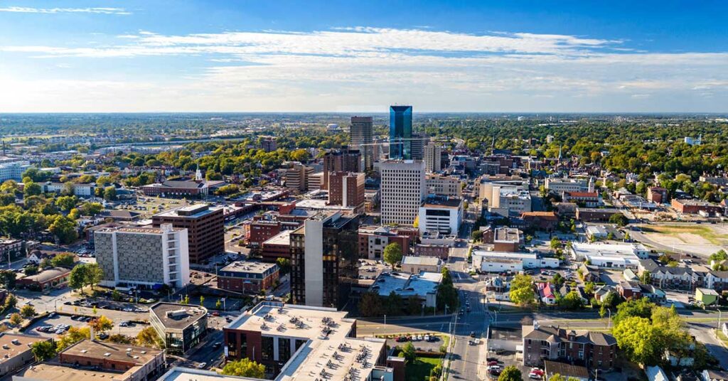 Aerial view of Downtown Lexington, Kentucky with a blue sky with clouds and the metropolitan area cityscape in the background.