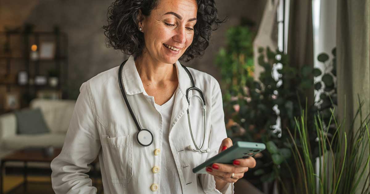 Mature woman doctor stand and use mobile phone at home
