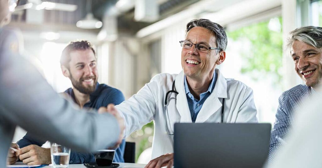 Happy doctor shaking hands with a businessman on a meeting in the office