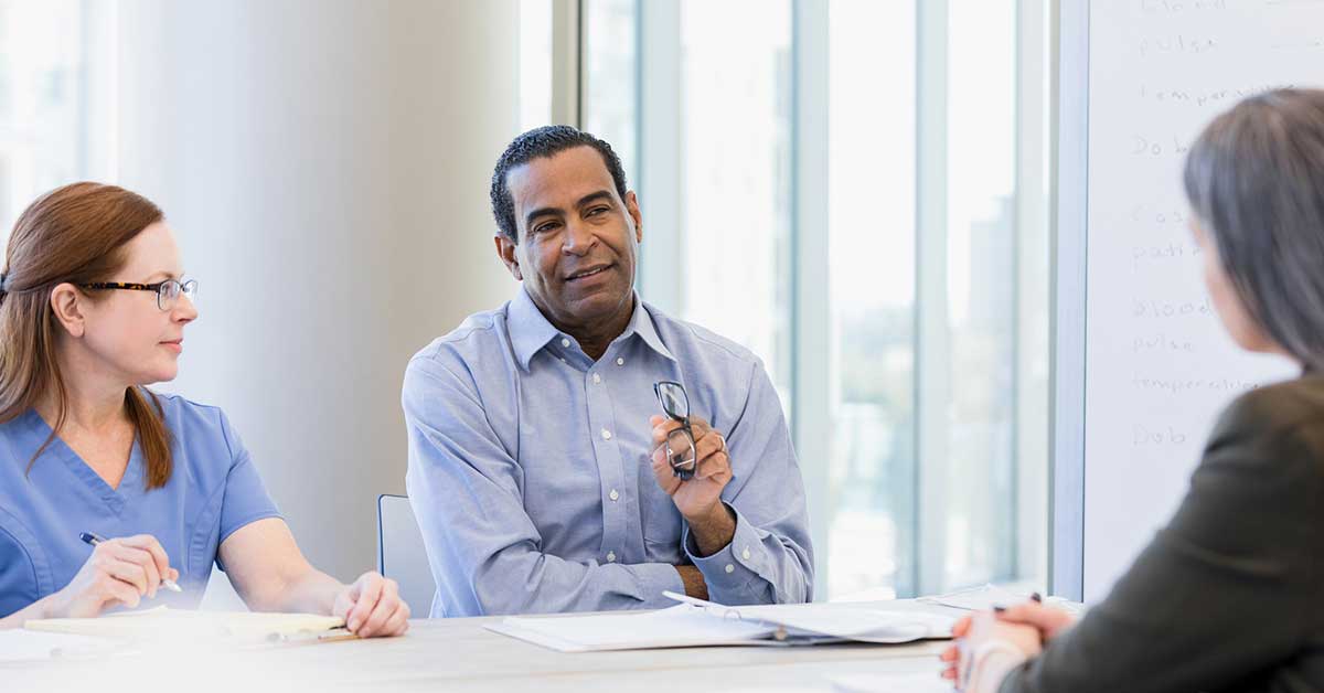 A male doctor in professional attire attentively discussing with a woman