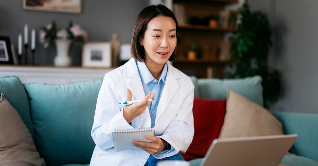 Asian doctor talking during a video call on a laptop from her home