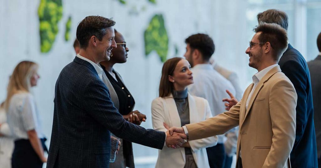 Two executives shaking hands at a business conference, networking and making connections.