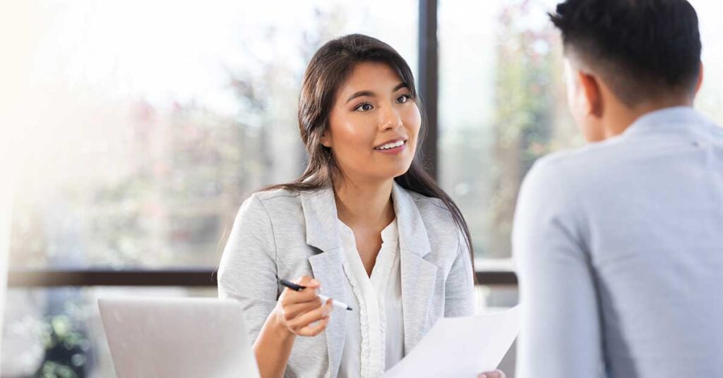 Young Asian woman attentively listening and holding documents