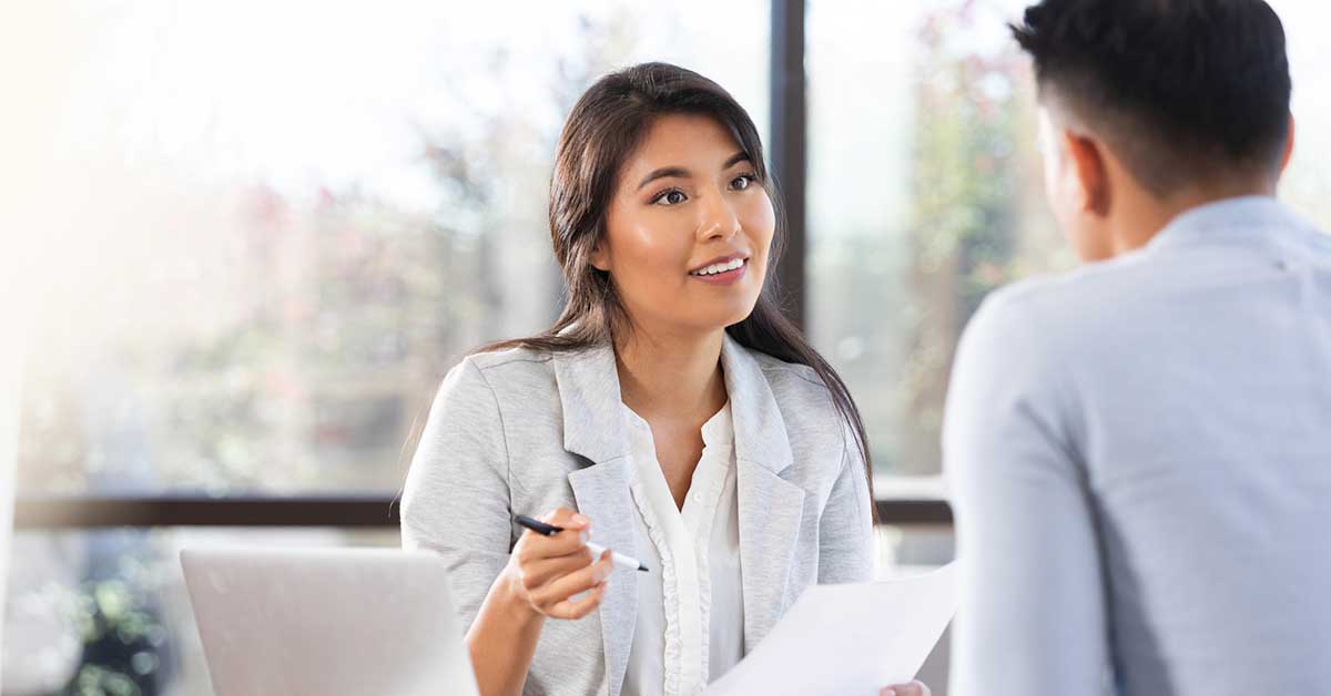Young Asian woman attentively listening and holding documents