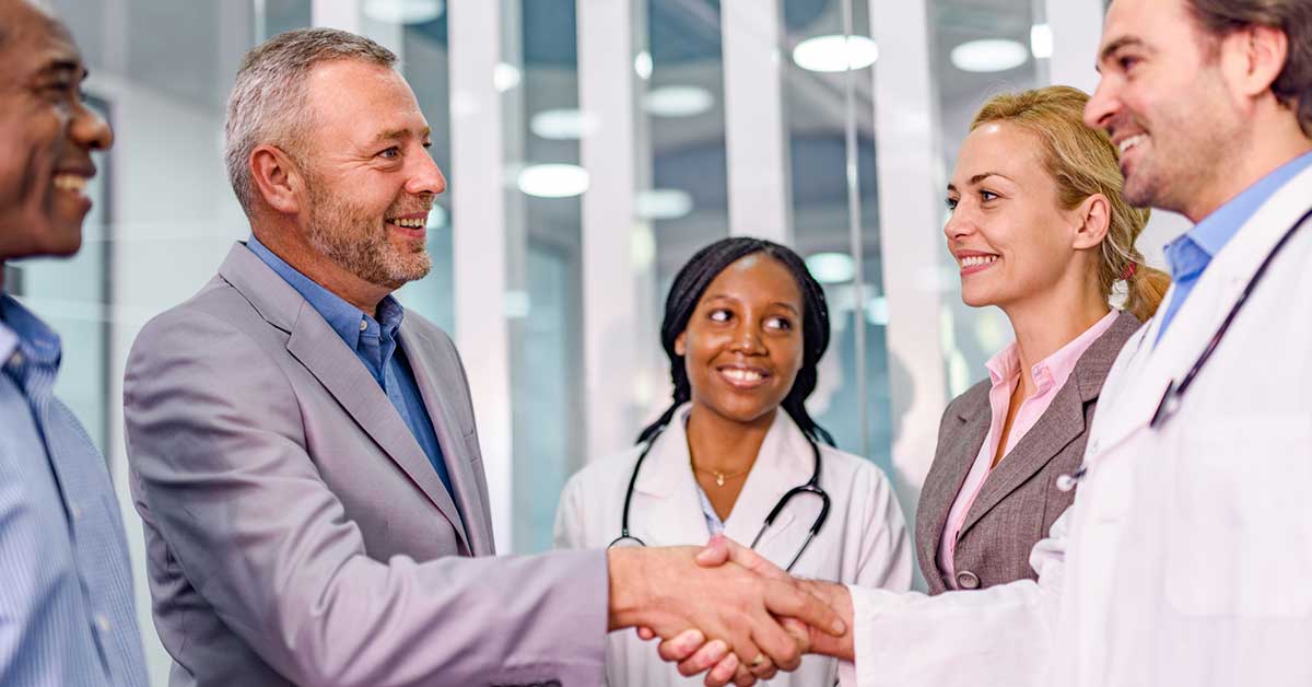 Mature businessman shaking hands with a doctor in the hospital