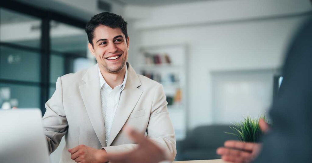 Shot of two confident business persons sitting on a desk in the office